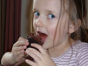 little girl licking a cupcake